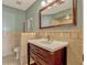 Bathroom featuring decorative tile, a cherry vanity with drawers, and framed mirror at 7217 Dr Phillips Blvd, Orlando, FL 32819