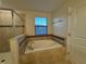 Bright bathroom featuring a large soaking tub with tiled surround and natural light at 7606 Loon Ave, Winter Garden, FL 34787