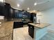 Bright kitchen featuring an island with granite countertops, stainless steel appliances and black cabinets at 7606 Loon Ave, Winter Garden, FL 34787