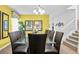 Bright dining area with a modern chandelier, yellow accent wall, and staircase at 9114 Stromboli Ct, Kissimmee, FL 34747