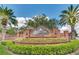 Community entrance with brick signage, vibrant landscaping, and mature palm trees at 10742 Boca Pointe Dr, Orlando, FL 32836