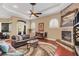 Warm living room boasting a stone fireplace, arched windows, and tray ceiling with wood floors at 10742 Boca Pointe Dr, Orlando, FL 32836