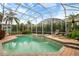 A beautiful screened-in pool area with spa, mature landscaping, and brick paver decking at 10742 Boca Pointe Dr, Orlando, FL 32836