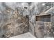 Close-up of shower with marble-like walls and gold accents with recessed shelf at 1109 Brownshire Ct, Longwood, FL 32779