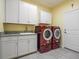 Well-equipped laundry room with granite counters, white cabinetry, sink, and modern red washer and dryer at 1132 Fins Up Ct, Daytona Beach, FL 32124