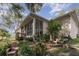 Lush backyard with screened-in porch, mature trees, and landscaped garden featuring sitting area with pink chairs at 1224 Shorecrest Cir, Clermont, FL 34711