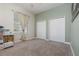 Cozy bedroom with neutral carpet, two closets, a light green accent wall and a window with decorative curtains at 1224 Shorecrest Cir, Clermont, FL 34711