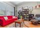 Cozy living room featuring a bright red sofa, bookshelves, hardwood floors, and a large window at 1224 Shorecrest Cir, Clermont, FL 34711