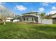 View of home's backyard with large screened in patio, lush lawn, and white privacy fence at 13631 Guildhall Cir, Orlando, FL 32828