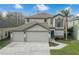 Beautiful two-story home boasts a three-car garage, manicured lawn, and welcoming entrance at 13631 Guildhall Cir, Orlando, FL 32828