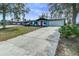 Home exterior with blue siding, a red door, mature trees, and landscaping at 1433 Ne Old Mill Dr, Deltona, FL 32725