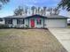 Charming single-story home with light blue paint, red front door, and a well-manicured yard at 1433 Ne Old Mill Dr, Deltona, FL 32725