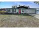 Charming exterior with a freshly painted blue siding, a red door, and landscaping at 1433 Ne Old Mill Dr, Deltona, FL 32725