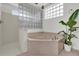 Bathroom featuring a soaking tub, walk-in shower, glass block window and decorative lighting at 14851 Oldham Dr, Orlando, FL 32826