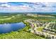 Aerial view of neighborhood featuring lake, surrounding greenery, and distant cityscape at 15318 Harvest Blvd, Clermont, FL 34714