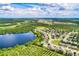 Aerial view of neighborhood featuring lake, surrounding greenery, and distant cityscape at 15318 Harvest Blvd, Clermont, FL 34714