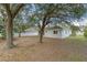 A view of the backyard featuring a well-maintained lawn, trees, and a white fence in the background at 15318 Harvest Blvd, Clermont, FL 34714