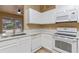 Well-lit kitchen features white cabinets, granite countertops, stainless steel sink, and modern appliances at 15318 Harvest Blvd, Clermont, FL 34714