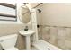 Bathroom featuring pedestal sink, black faucet, round mirror, and tiled shower with curtain at 2006 N Westmoreland Dr, Orlando, FL 32804