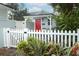 Charming front entrance with a red door, white picket fence, and vibrant greenery at 2006 N Westmoreland Dr, Orlando, FL 32804