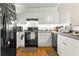 Galley style kitchen with white cabinets, black appliances, and wood-look flooring at 206 E South St # 1030, Orlando, FL 32801