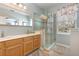 Bathroom featuring double sinks, natural wood cabinets, large mirror, and glass enclosed shower at 206 Norfolk Pl, Kissimmee, FL 34747