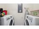 A well-lit laundry room featuring a washer, dryer, ironing board, and electrical panel at 3422 Seneca Club Loop # 57, Orlando, FL 32808