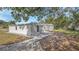 Exterior side view of a charming white home with a concrete path surrounded by lush greenery and trees at 5108 Balboa Dr, Orlando, FL 32808