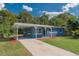 Charming single-story home with blue stone accents, a well-manicured lawn, and a covered carport and long driveway at 705 Liberty St, Eustis, FL 32726