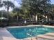 Community swimming pool area with palm trees, lounge chairs, and umbrellas for relaxing by the pool at 7123 Yacht Basin Ave # 328, Orlando, FL 32835