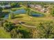 Scenic aerial view showcasing a golf course with a pond, sand traps and surrounding trees at 7296 Sw 115Th Pl, Ocala, FL 34476