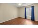 Neutral bedroom featuring a ceiling fan, hardwood floors, and large window with blue curtains at 7296 Sw 115Th Pl, Ocala, FL 34476