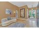 Elegant living room featuring a stylish curved sofa, tile floors, contemporary artwork and an ornate mirror on the wall at 824 Preserve Ter, Lake Mary, FL 32746