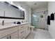 Bright bathroom featuring double sinks, granite counters, and frameless glass shower with marble tile at 8443 Via Bella Notte, Orlando, FL 32836