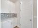 Laundry room with white cabinets, modern hardware, and tile backsplash at 9014 Sonoma Coast Dr, Winter Garden, FL 34787