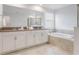 This bathroom features double sinks, a large soaking tub, and white cabinetry at 9752 Petition Way, Orlando, FL 32832