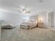 A main bedroom with a ceiling fan, sitting area, neutral colors, carpet, and an ensuite bath at 9752 Petition Way, Orlando, FL 32832