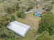 Areal view of home with pool and adjacent three-bay storage building on wooded lot at 1134 Glenwood Rd, Deland, FL 32720