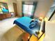 Bright bedroom with blue bedding, dresser, and a window with patterned curtains at 124 Godfrey Rd, Edgewater, FL 32141