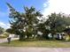 Landscaped front yard with mature trees, green lawn, and vintage Airstream trailer at 124 Godfrey Rd, Edgewater, FL 32141