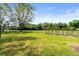Expansive back yard with green grass, mature trees, and a classic black metal fence at 1312 Winter Springs Blvd, Winter Springs, FL 32708