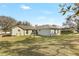 Spacious backyard featuring lush green grass, mature trees and a screened-in porch in the distance at 154 Desiree Aurora St, Winter Garden, FL 34787
