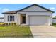 A single-Gathering home with a well-manicured lawn, a driveway leading to a two-car garage and modern finishes at 16390 Blooming Cherry Dr, Groveland, FL 34736