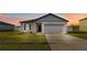Charming single-Gathering home featuring a well-maintained lawn and a two-car garage under a warm, colorful sunset at 16390 Blooming Cherry Dr, Groveland, FL 34736