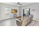 Living room with wood-look floors, modern ceiling fan, leather sofa, flat screen tv and sliding glass door to backyard at 16390 Blooming Cherry Dr, Groveland, FL 34736