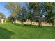 Expansive backyard featuring lush green grass and mature trees along the edge of a golf course at 182 Crepe Myrtle Dr, Groveland, FL 34736