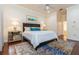 Well-lit bedroom with a king bed, mirrored nightstand, and hardwood floors at 182 Crepe Myrtle Dr, Groveland, FL 34736