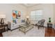 Cozy living room with plush seating, bright artwork, large windows, and a soft carpet on wood floor at 182 Crepe Myrtle Dr, Groveland, FL 34736