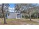 View of the metal barn with roll-up door, pedestrian door and blue trim at 255 Butterfly Forest Rd, Geneva, FL 32732