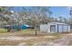 Exterior view of the residence and the metal barn with blue trim and roll-up doors at 255 Butterfly Forest Rd, Geneva, FL 32732
